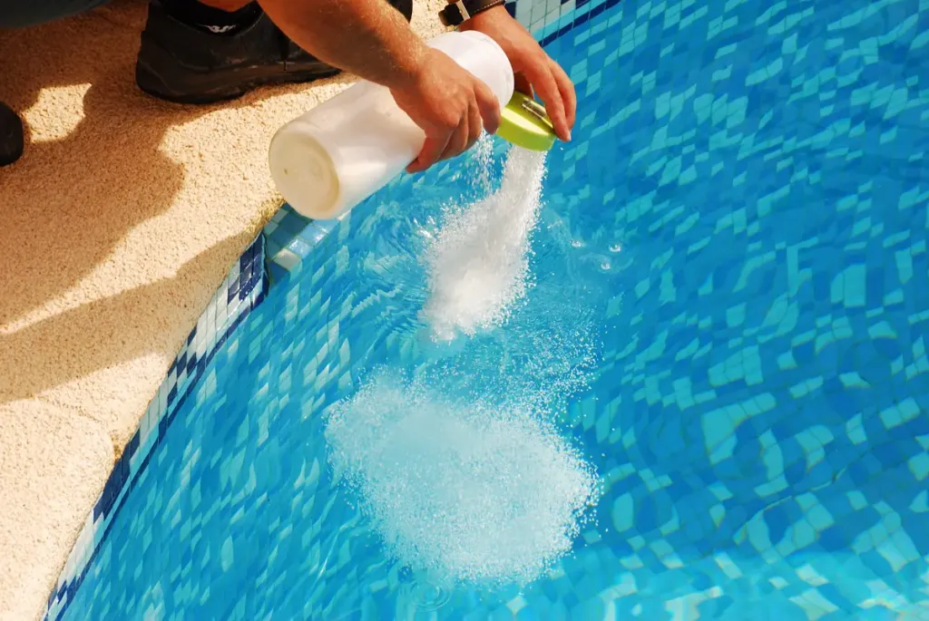 homme déversant un produit d'entretien de piscine dans une piscine